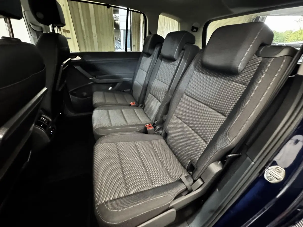 Vue intérieure côté droit sur la deuxième rangée de sièges gris du Volkswagen Touran 2024 bleu, version 7 places.