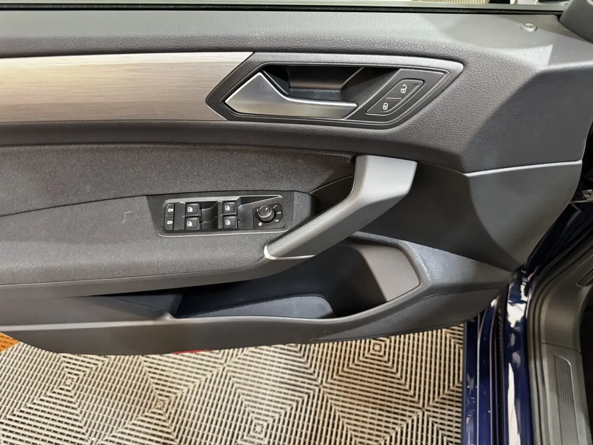 Vue rapprochée de la porte avant gauche du Volkswagen Touran bleu 2024 avec commandes de vitres et verrouillage.