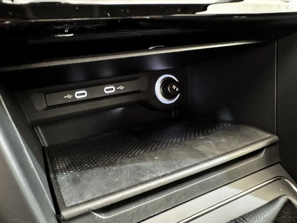 Gros plan intérieur sur la console centrale noire du Volkswagen Touran 2024 avec ports USB-C et prise 12V éclairée.