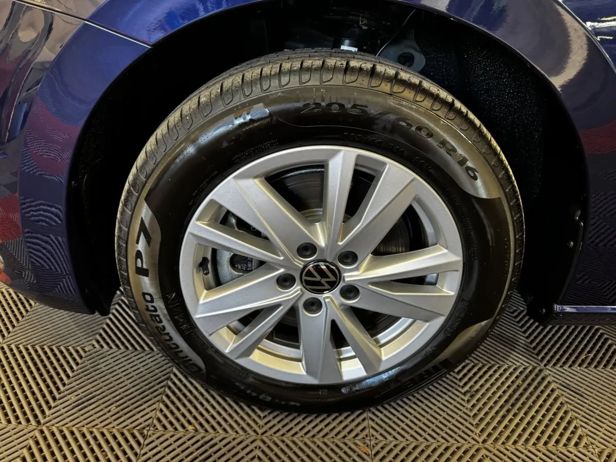Gros plan sur la roue avant gauche du Volkswagen Touran bleu 2024 avec jante alliage argentée et pneu Pirelli.