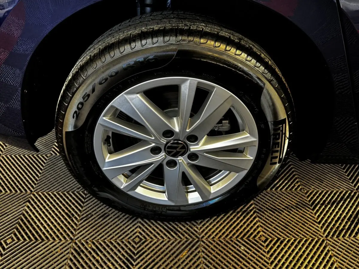 Gros plan sur la roue avant droite du Volkswagen Touran bleu 2024 avec jante alliage et pneu Pirelli.