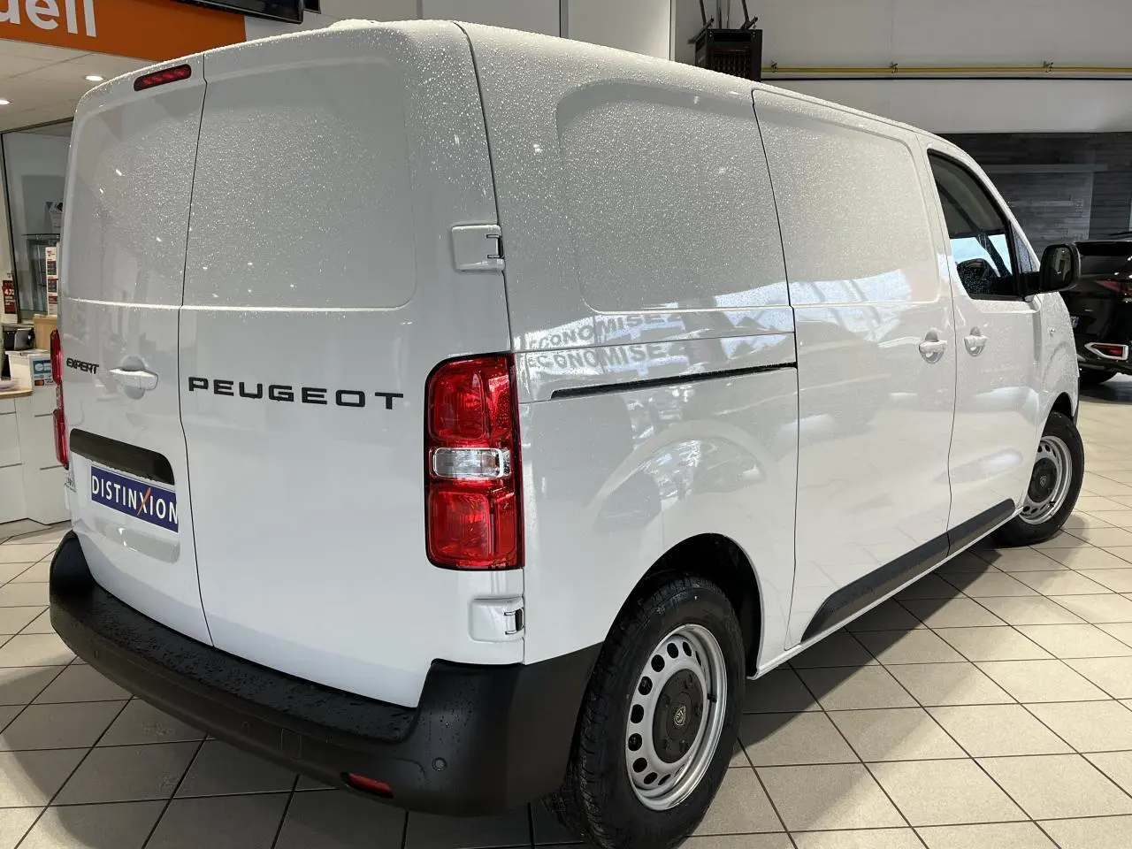 Vue 3/4 arrière droite du Peugeot Expert Fourgon blanc 2024, avec feux arrière rouges et pare-chocs noir.