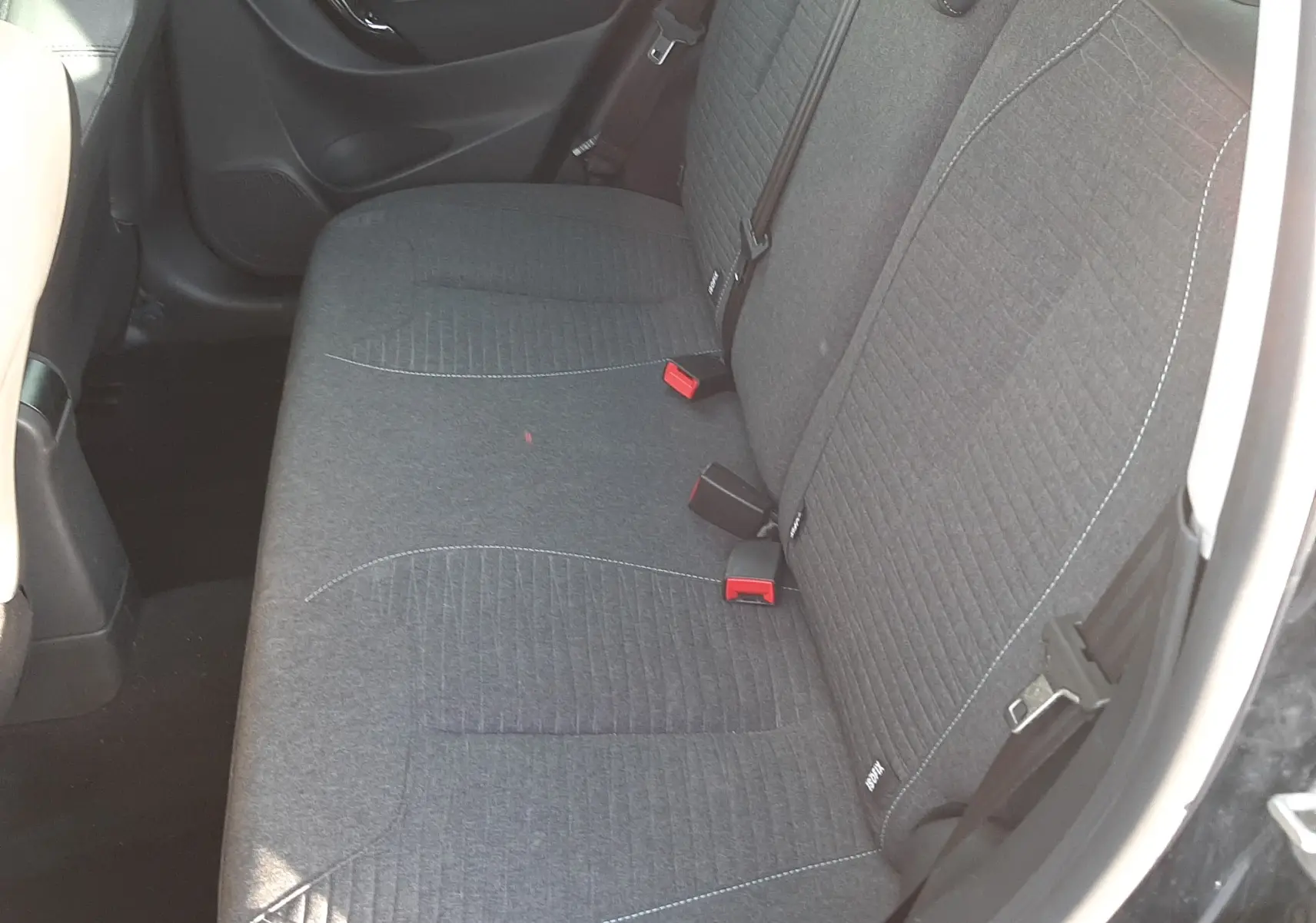 Vue intérieure côté droit montrant la banquette arrière en tissu gris de la Citroën C3 noire de 2016.