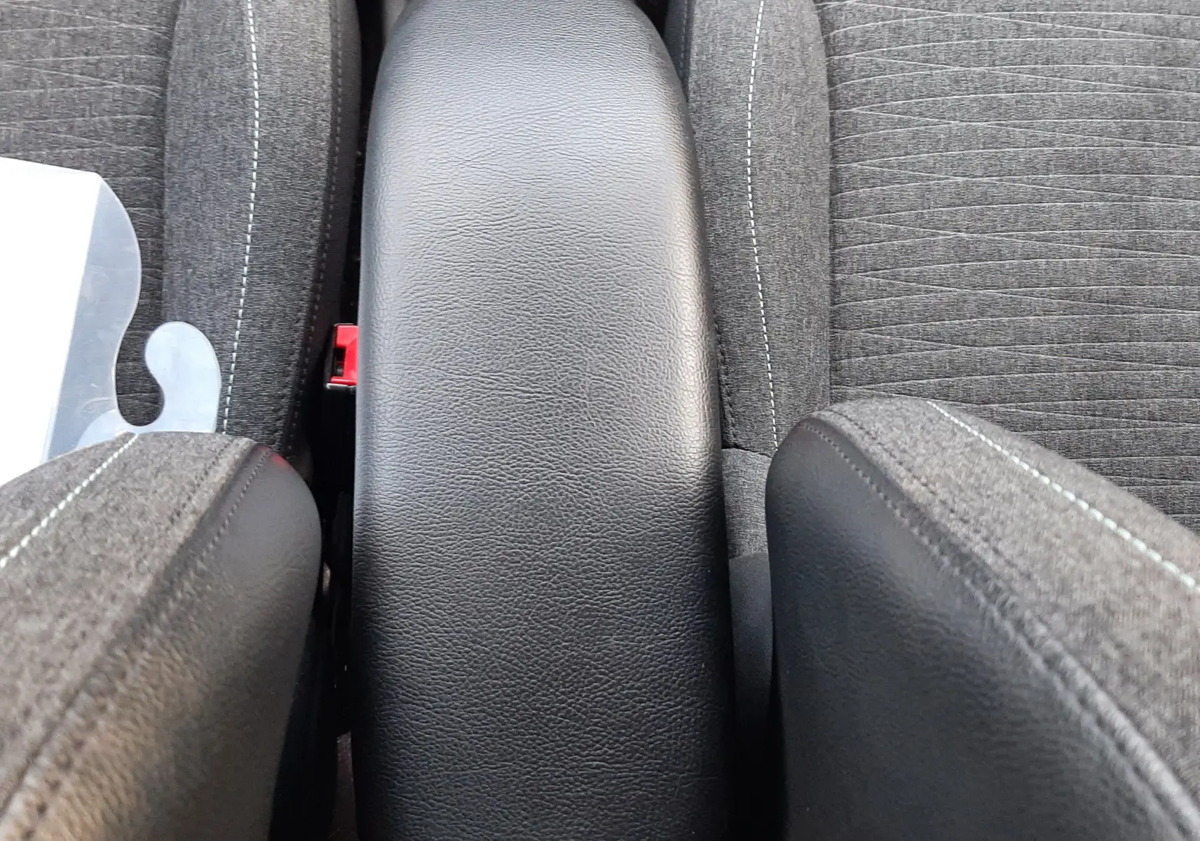 Vue plongeante sur l'accoudoir central noir entre les sièges avant gris tissu de la Citroën C3 BlueHDi 2016.