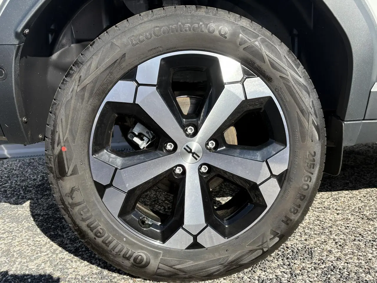 Vue rapprochée sur la roue arrière droite d’un Dacia Duster blanc métallisé 2024 avec jante alliage noire.