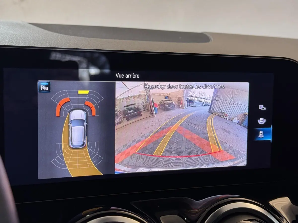 Écran tactile intérieur montrant la caméra de recul et l’aide au stationnement du Mercedes GLA 250 e gris foncé.