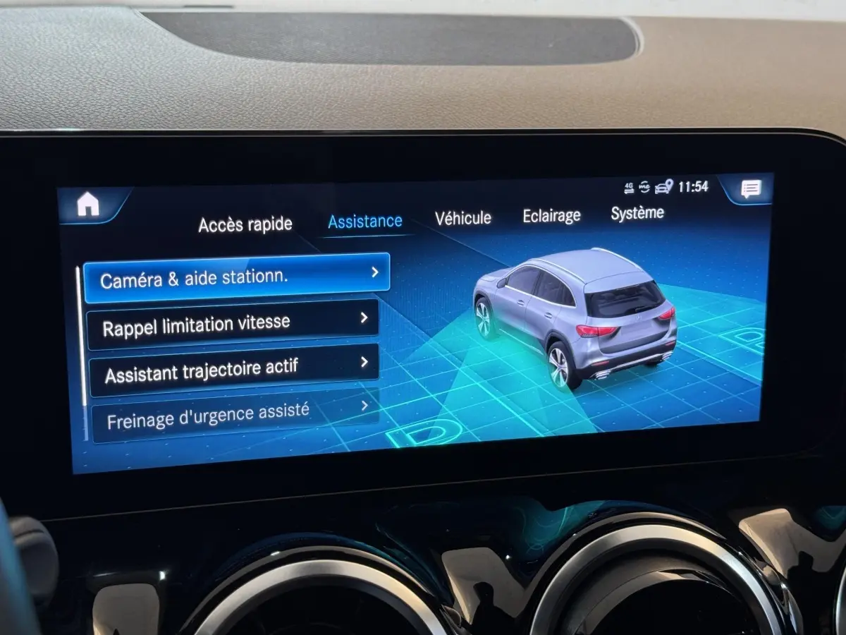Écran tactile intérieur montrant l'assistance au stationnement avec une vue 3/4 arrière virtuelle du Mercedes GLA gris foncé.