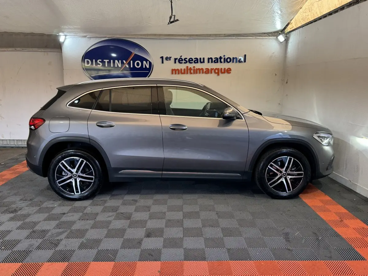 Vue de profil côté gauche d’un Mercedes GLA 250 e Business Line gris foncé avec jantes alliage et toit noir dans un showroom.