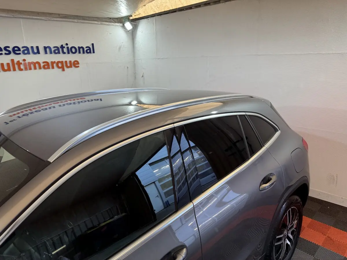 Vue 3/4 arrière droite d’un Mercedes GLA 250 e Business Line gris foncé avec barres de toit chromées et vitres teintées.