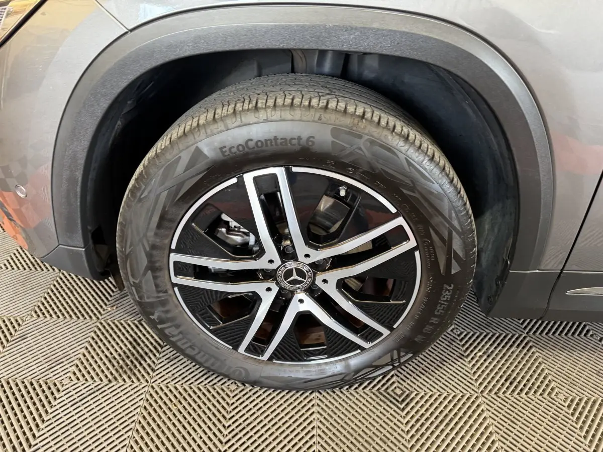 Gros plan sur la roue avant droite d’un Mercedes GLA 250 e gris foncé avec jante alliage noir et argent.