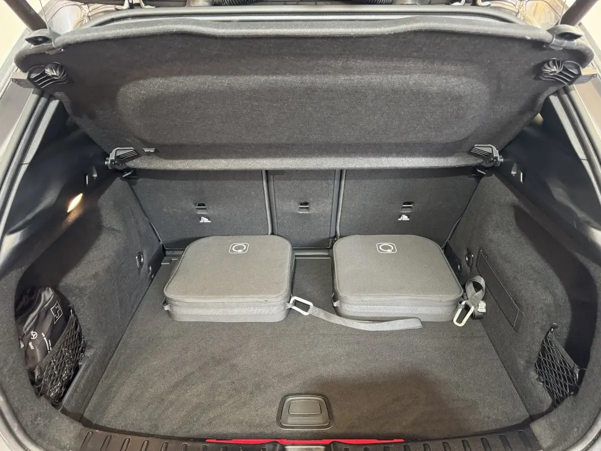 Coffre ouvert vu de face d’un Mercedes GLA 250 e Business Line gris foncé avec deux valises de recharge posées.