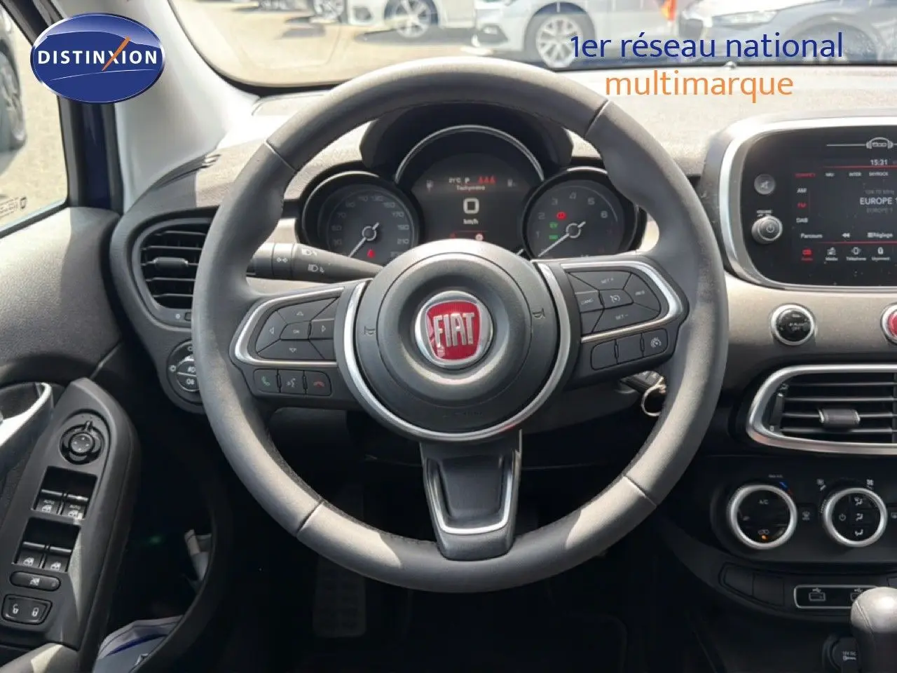 Vue intérieure centrée sur le volant du Fiat 500X 2024, avec tableau de bord et commandes visibles en noir.