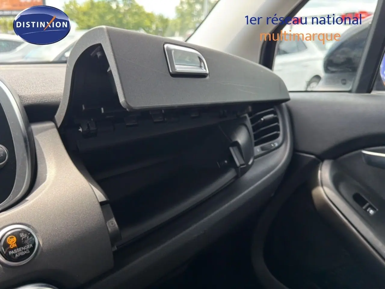 Intérieur de la FIAT 500X 2024 montrant la boîte à gants ouverte côté passager avec tableau de bord noir.