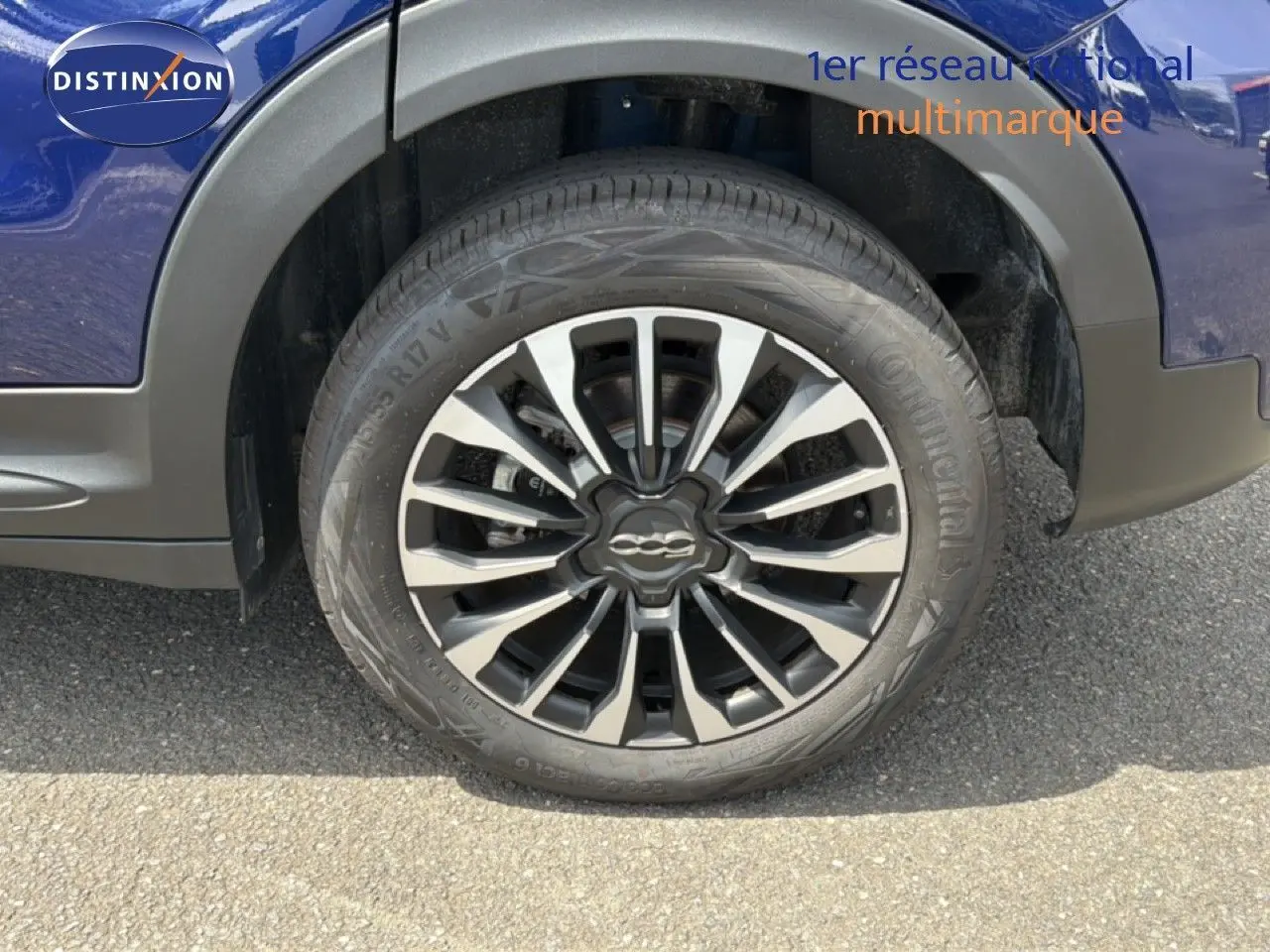 Gros plan sur la roue avant droite d’un FIAT 500X bleu Venezia avec jante alliage bicolore et logo central.