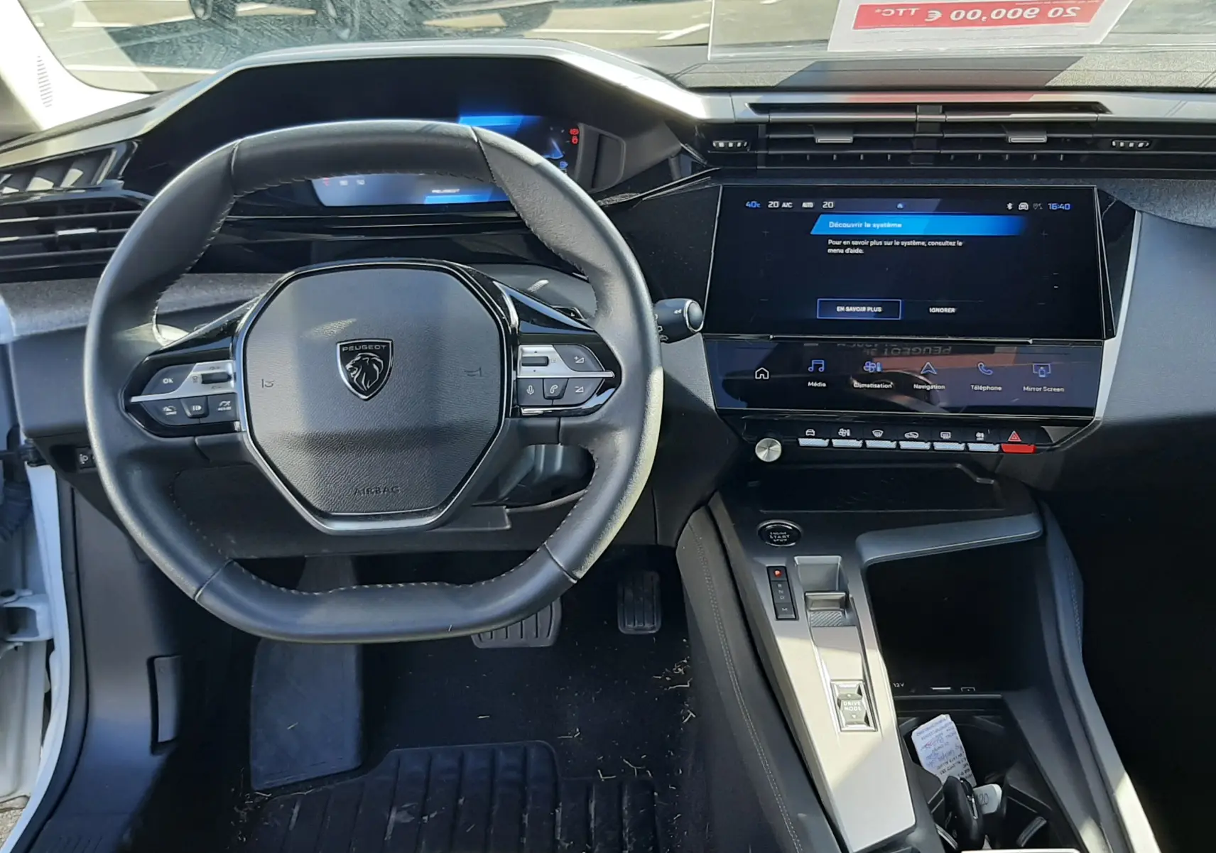 Vue intérieure centrée sur le volant et la console centrale d'une Peugeot 308 blanche 2024 avec écran tactile et commandes au volant.