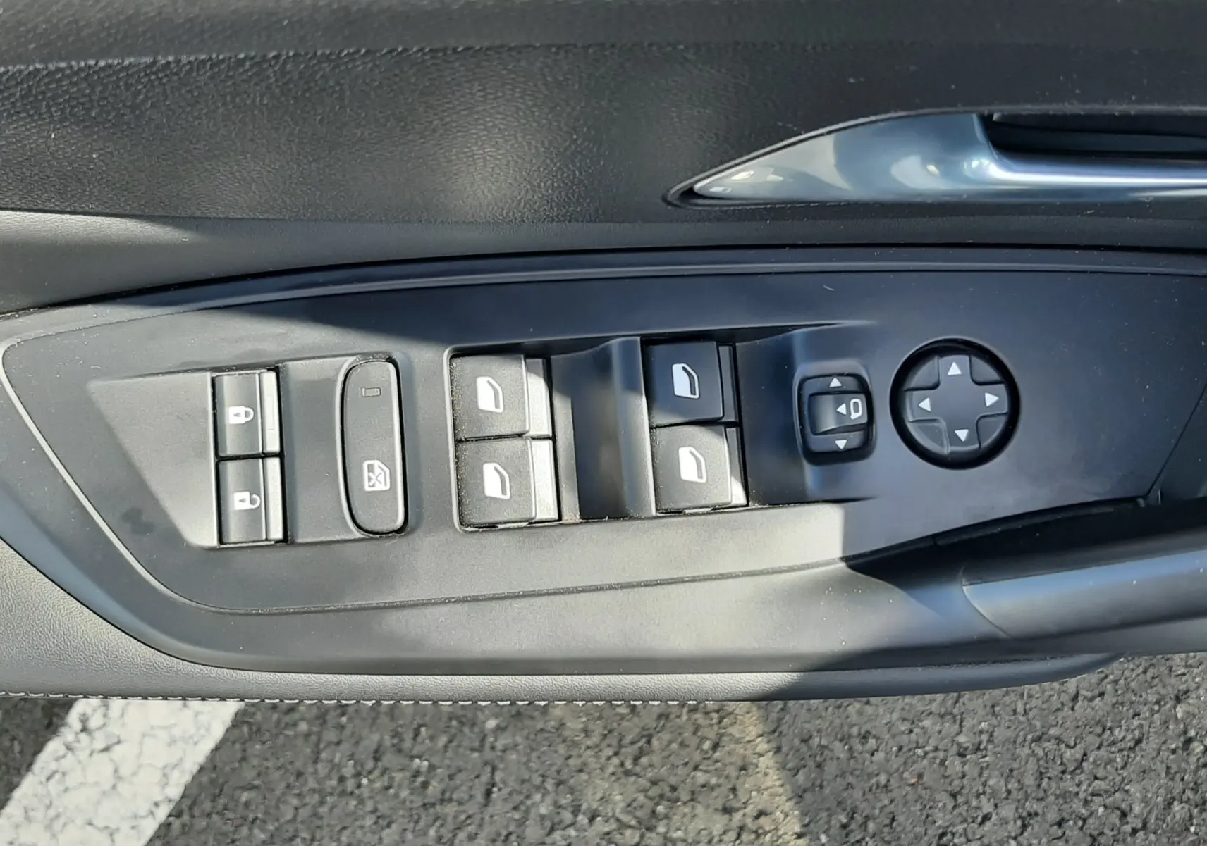 Panneau de commandes des vitres et rétroviseurs côté conducteur de la Peugeot 308 blanche 2024, intérieur noir.