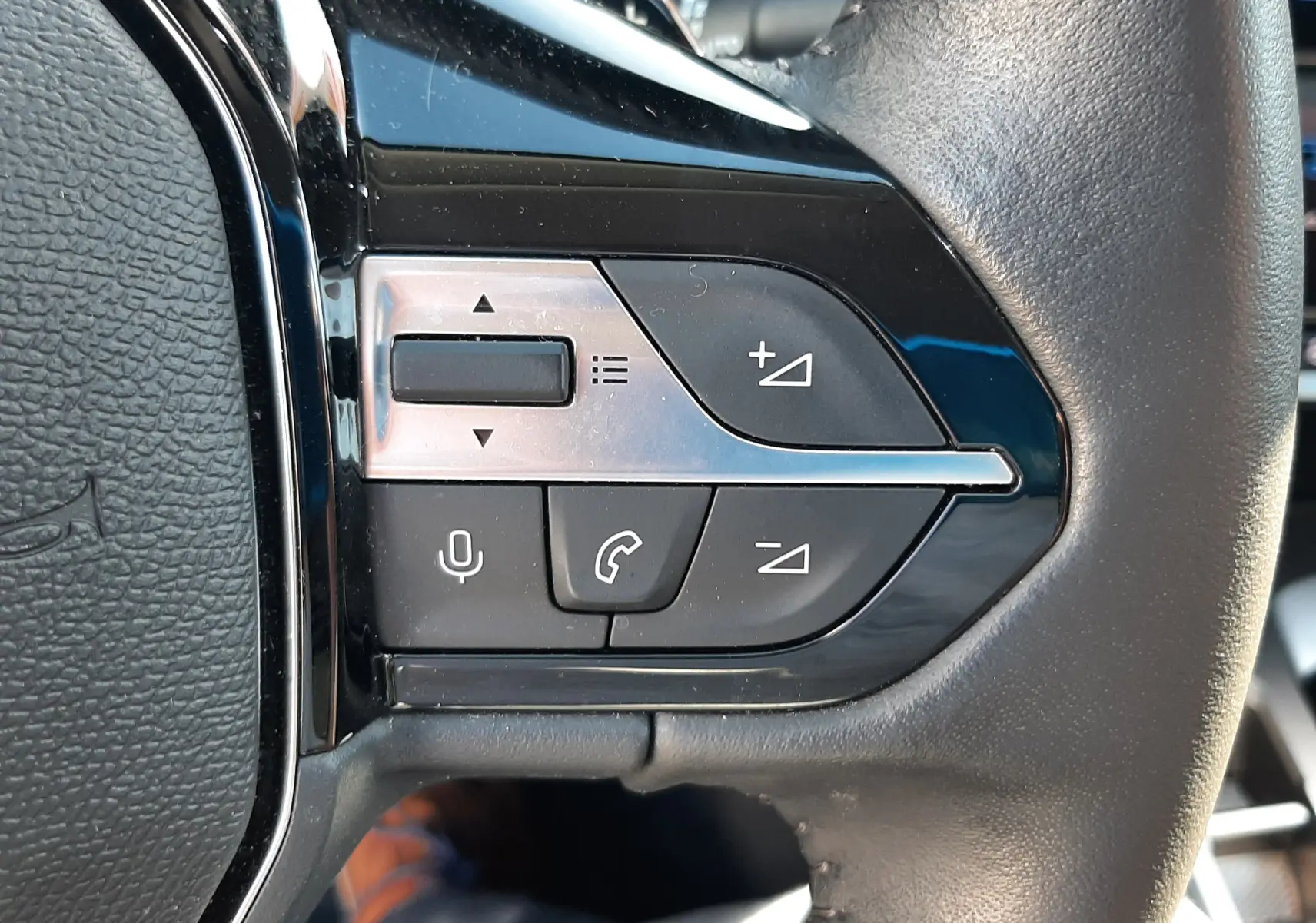 Gros plan sur les commandes multifonctions côté gauche du volant en cuir noir d'une Peugeot 308 blanche 2024.