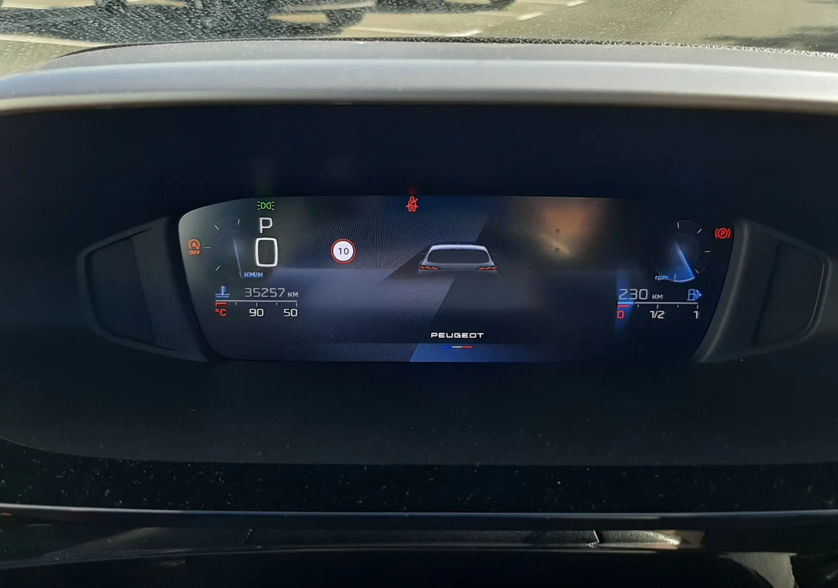 Tableau de bord numérique de Peugeot 308 2024, affichage central avec indicateurs de vitesse et autonomie, vue intérieure frontale.