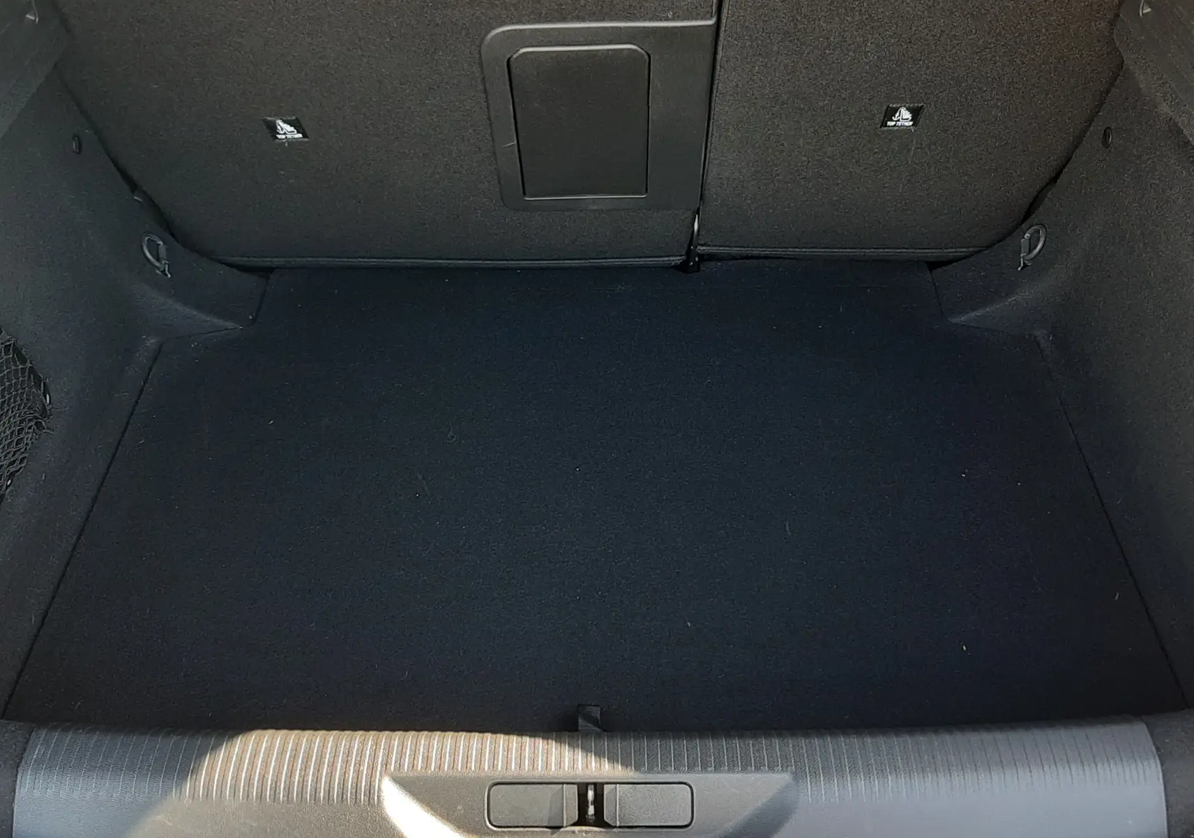 Vue intérieure du coffre noir d'une Peugeot 308 blanche 2024, espace vide et propre avec ouverture large.