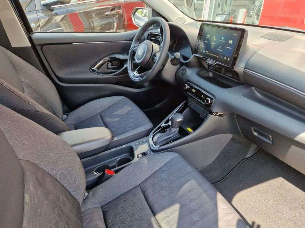 Intérieur de la Toyota Yaris 2025 gris minéral, vue côté conducteur, tableau de bord moderne avec écran tactile et boîte auto.