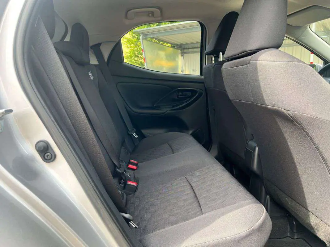 Vue intérieure côté gauche des sièges arrière en tissu gris foncé de la Toyota Yaris 1.5 Hybrid 2025 gris minéral.