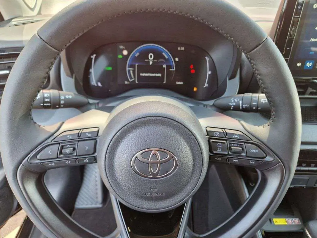 Vue rapprochée du volant noir de la Toyota Yaris 2025 hybride avec commandes intégrées et tableau de bord digital.