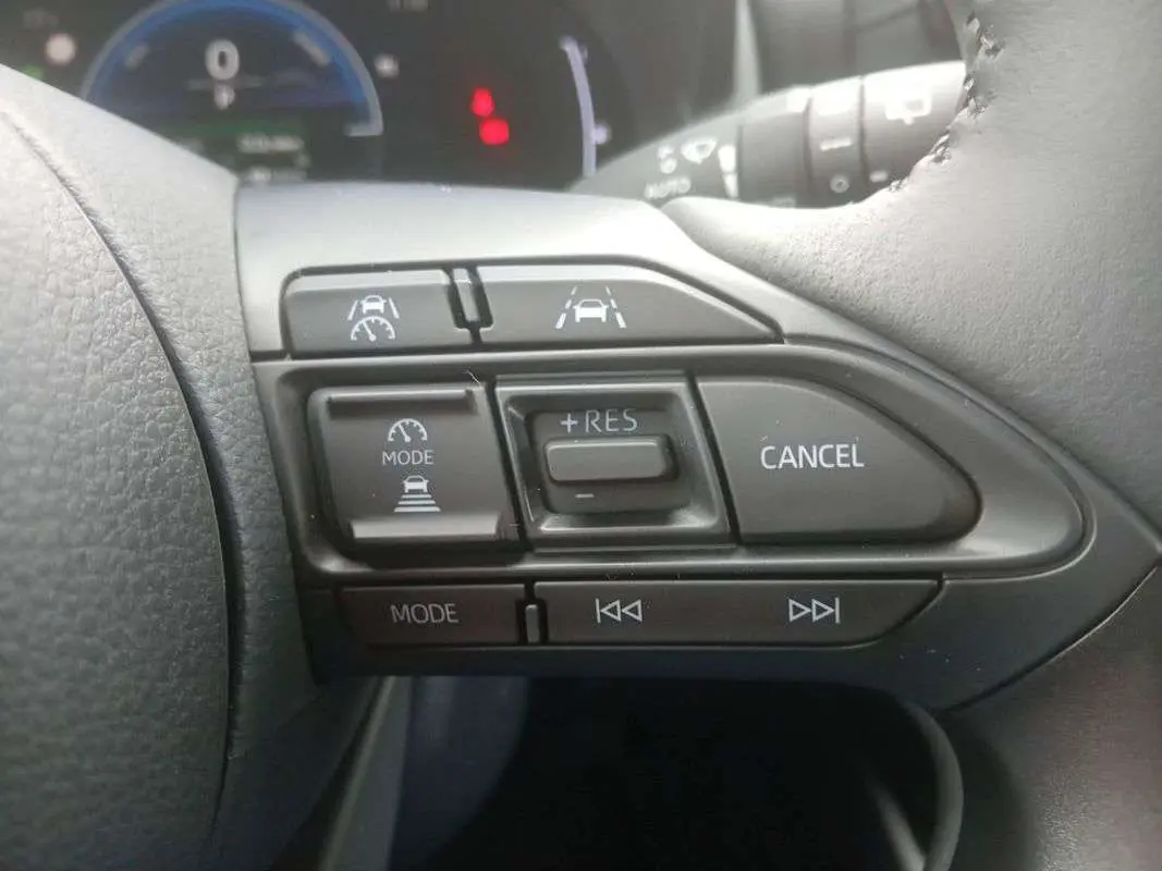 Gros plan sur les commandes au volant droit de la Toyota Yaris 2025 gris minéral, avec régulateur de vitesse et aides à la conduite.