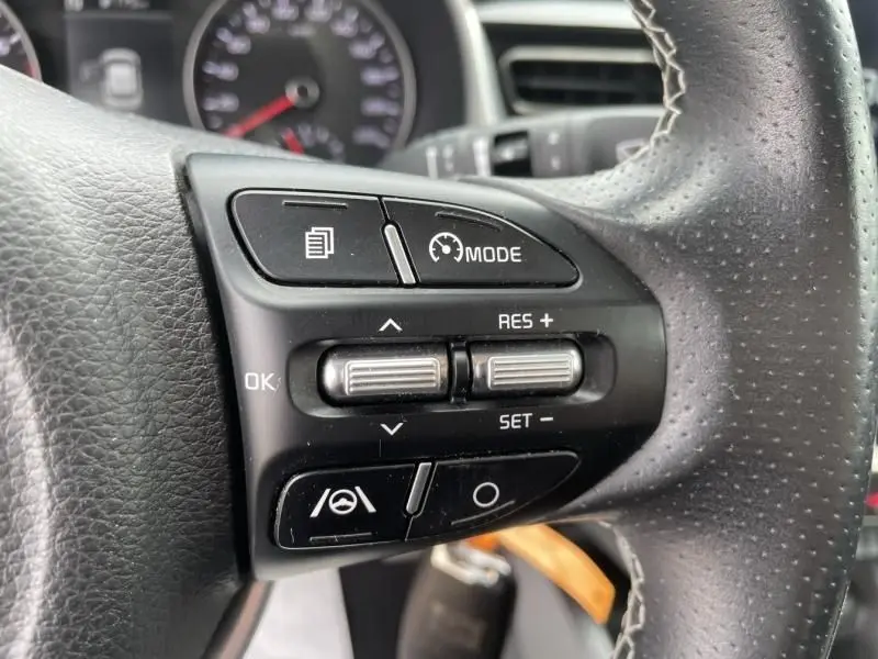 Gros plan sur les commandes au volant côté gauche d'une BMW Série 1 F20 135i bleu métal, avec régulateur de vitesse.