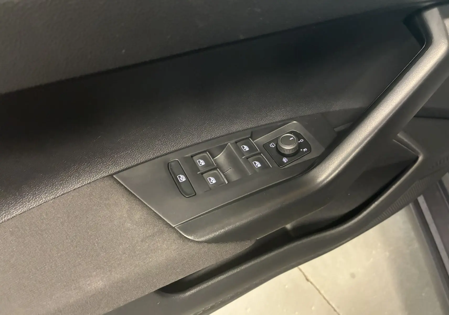 Vue rapprochée des commandes des vitres et des rétroviseurs sur la porte côté conducteur du Volkswagen Taigo gris 2023.