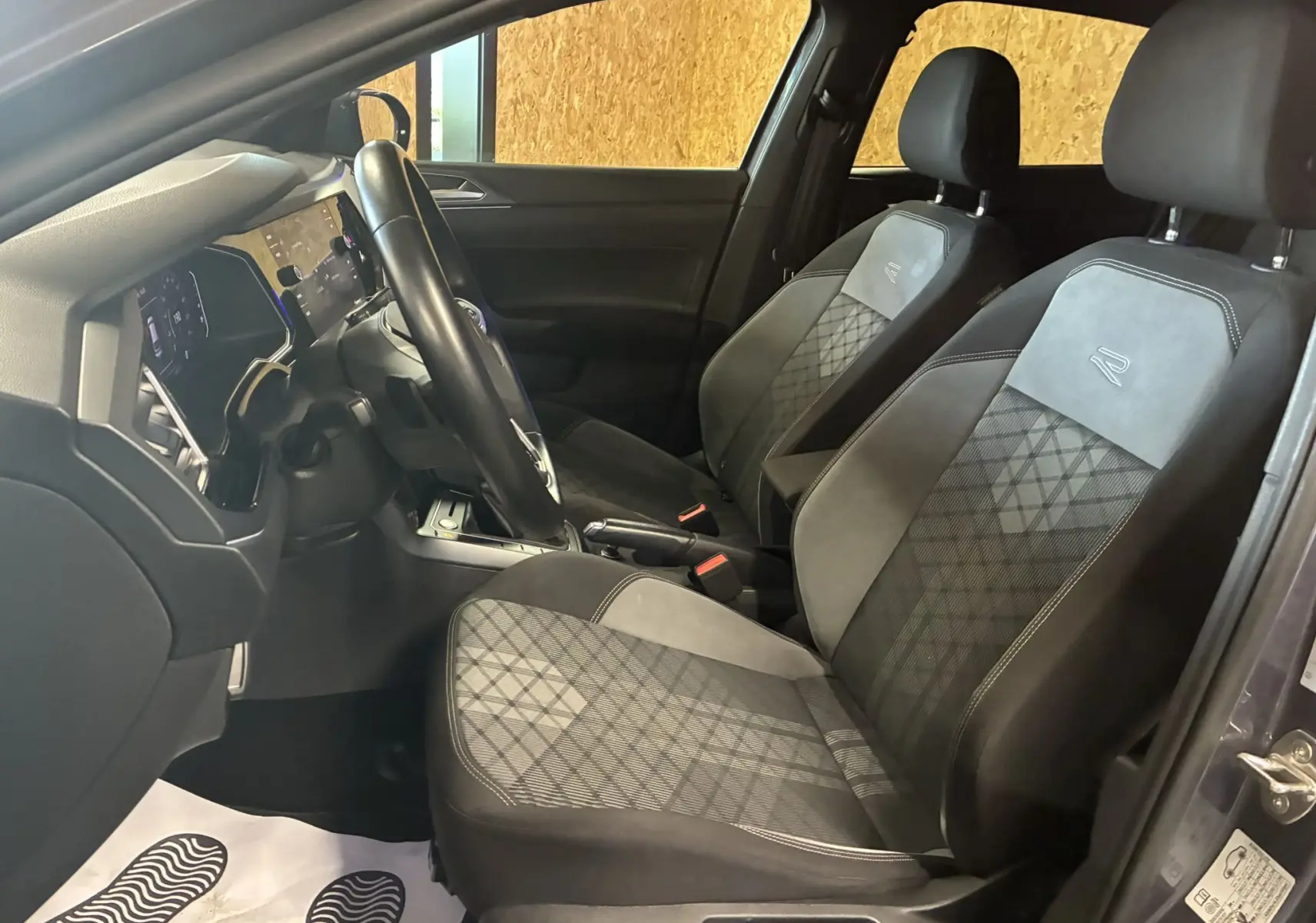Vue intérieure côté conducteur du Volkswagen Taigo 1.5 TSI R-Line 2023, sièges tissu gris noir avec logo R brodé.