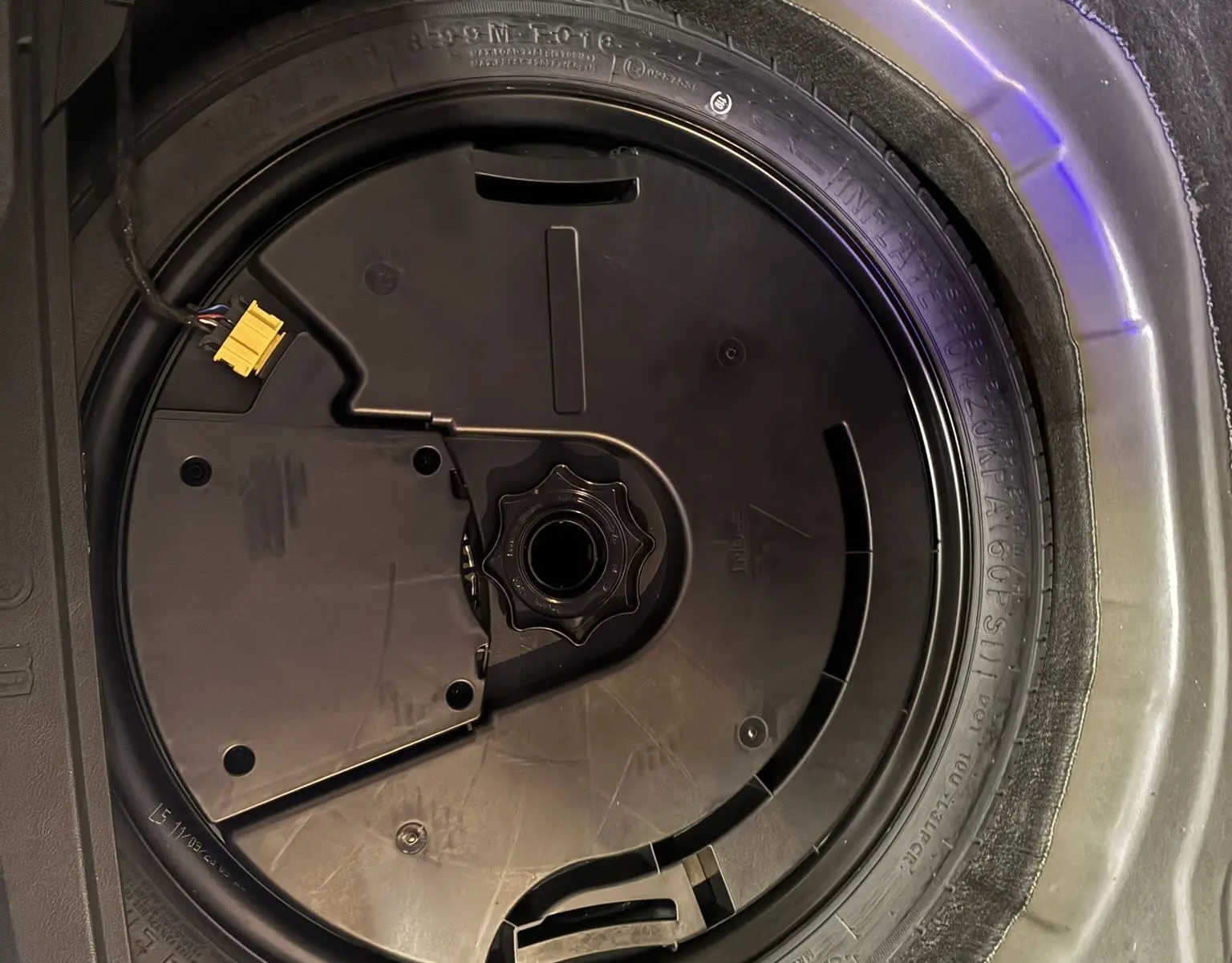 Gros plan sur la roue de secours noire dans le coffre du Volkswagen Taigo gris 2023, version 1.5 TSI R-LINE.