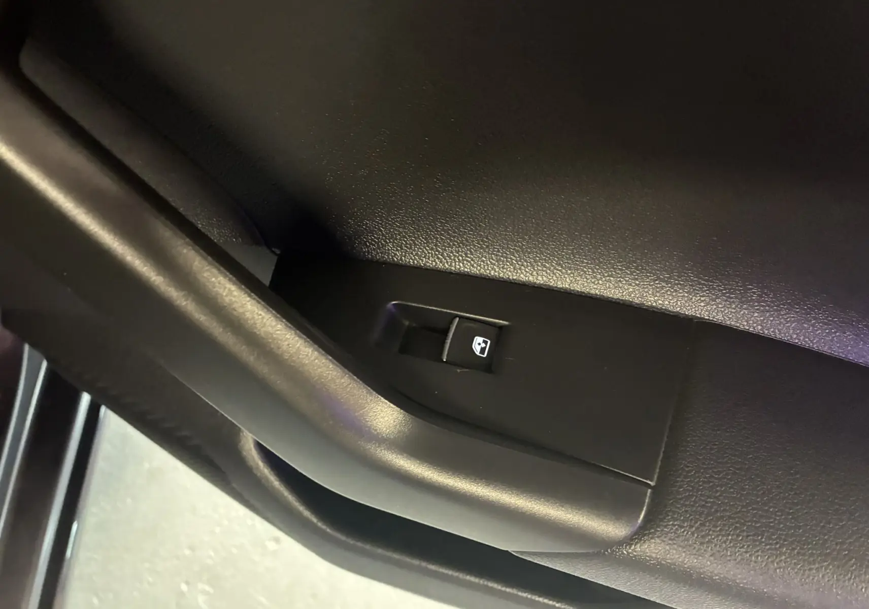 Bouton de commande de lève-vitre sur la porte intérieure noire d'un Volkswagen Taigo gris 2023 finition R-LINE.