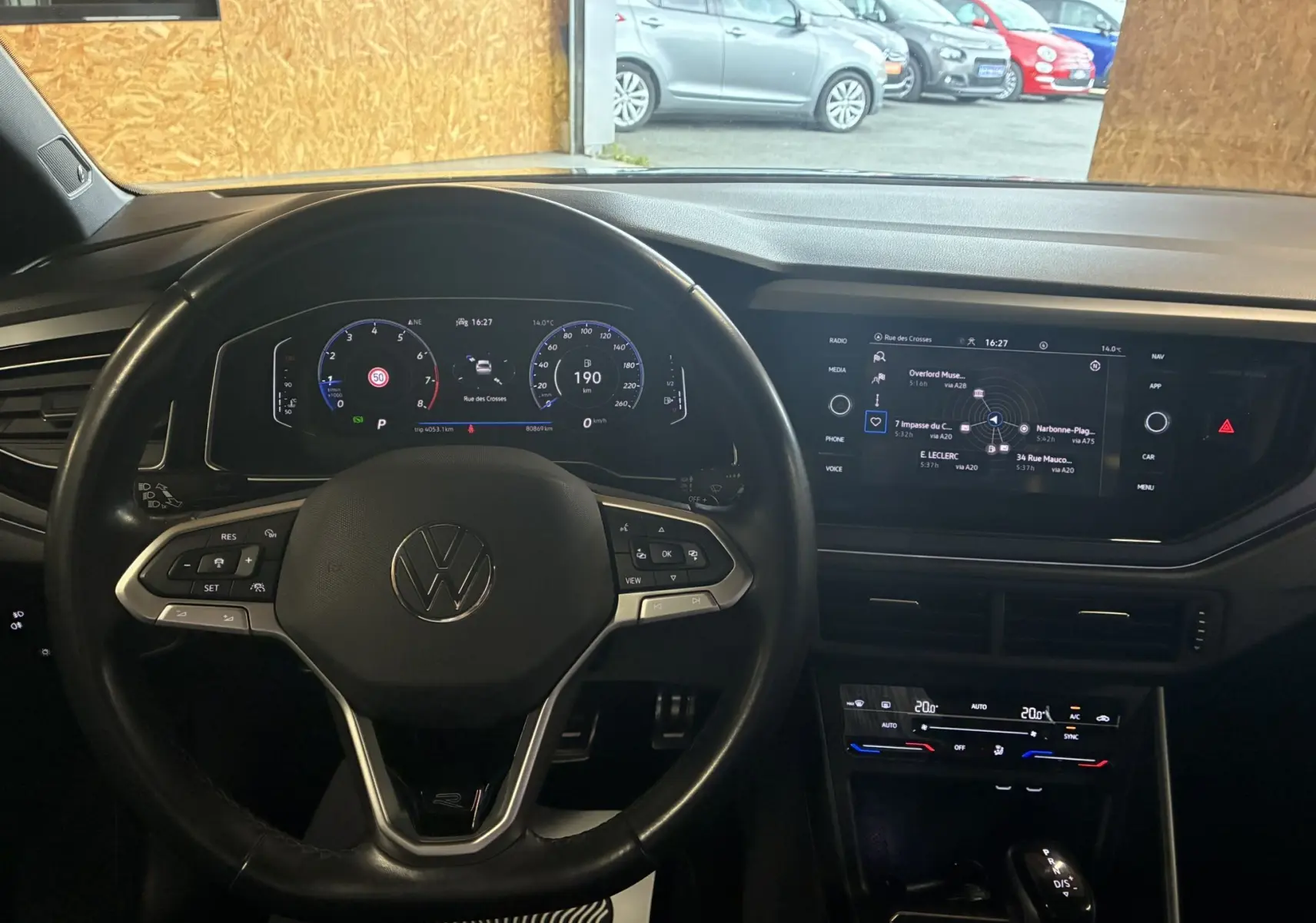 Vue intérieure du volant et tableau de bord numérique du Volkswagen Taigo gris 2023 avec écran tactile central et commandes au volant.