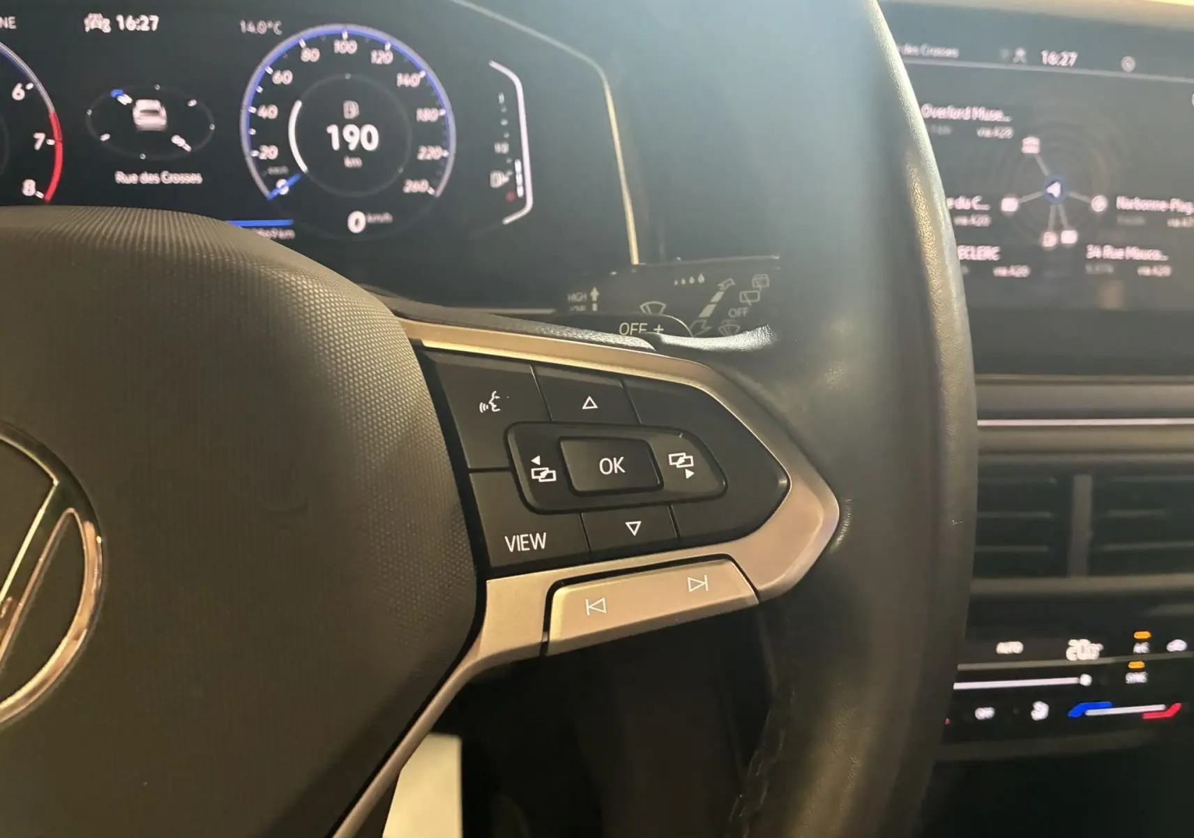 Gros plan sur le côté gauche du volant du Volkswagen Taigo gris 2023, avec commandes multifonctions et tableau de bord numérique.