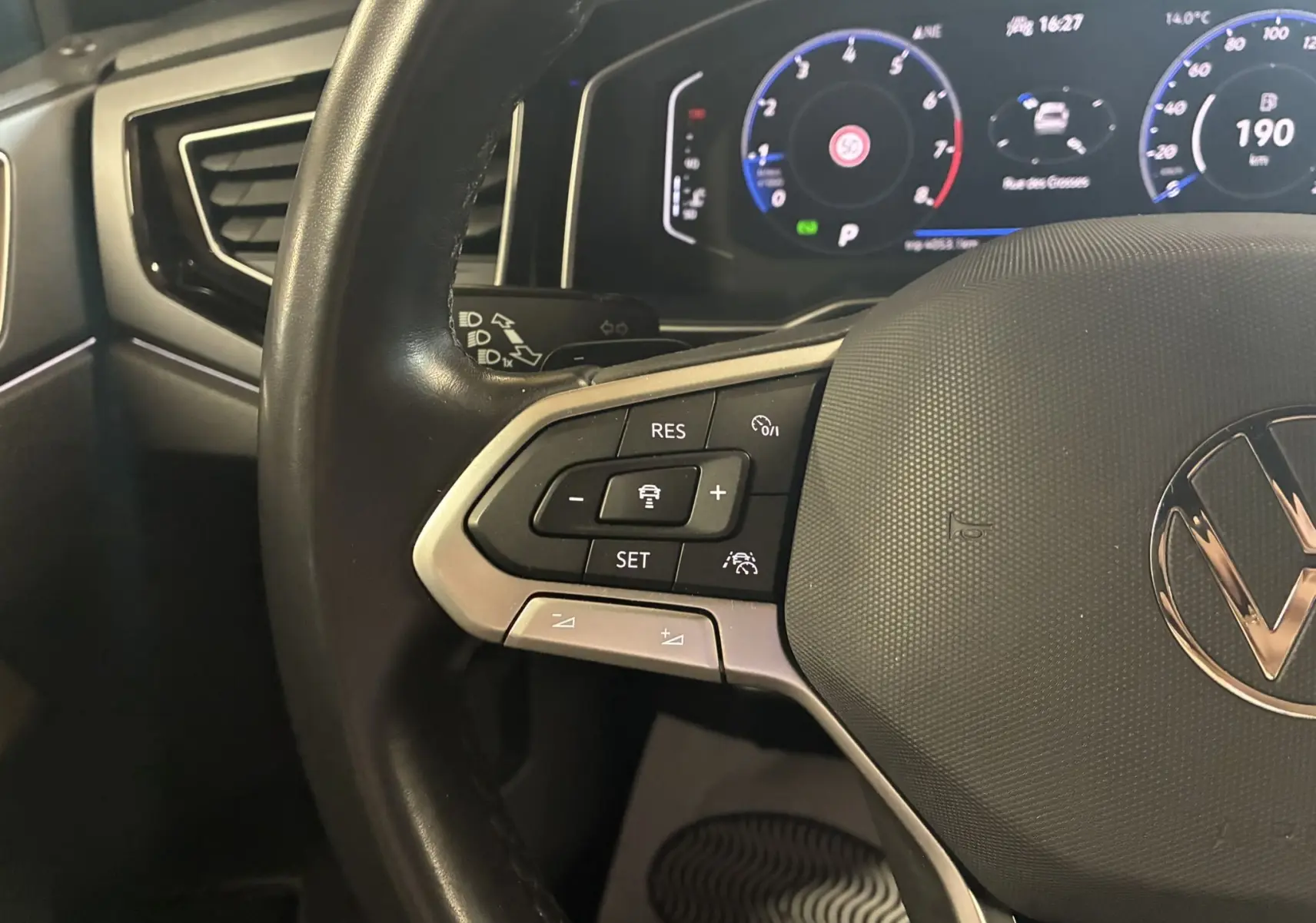 Gros plan sur le volant noir du Volkswagen Taigo 2023 avec commandes intégrées et tableau de bord numérique lumineux.