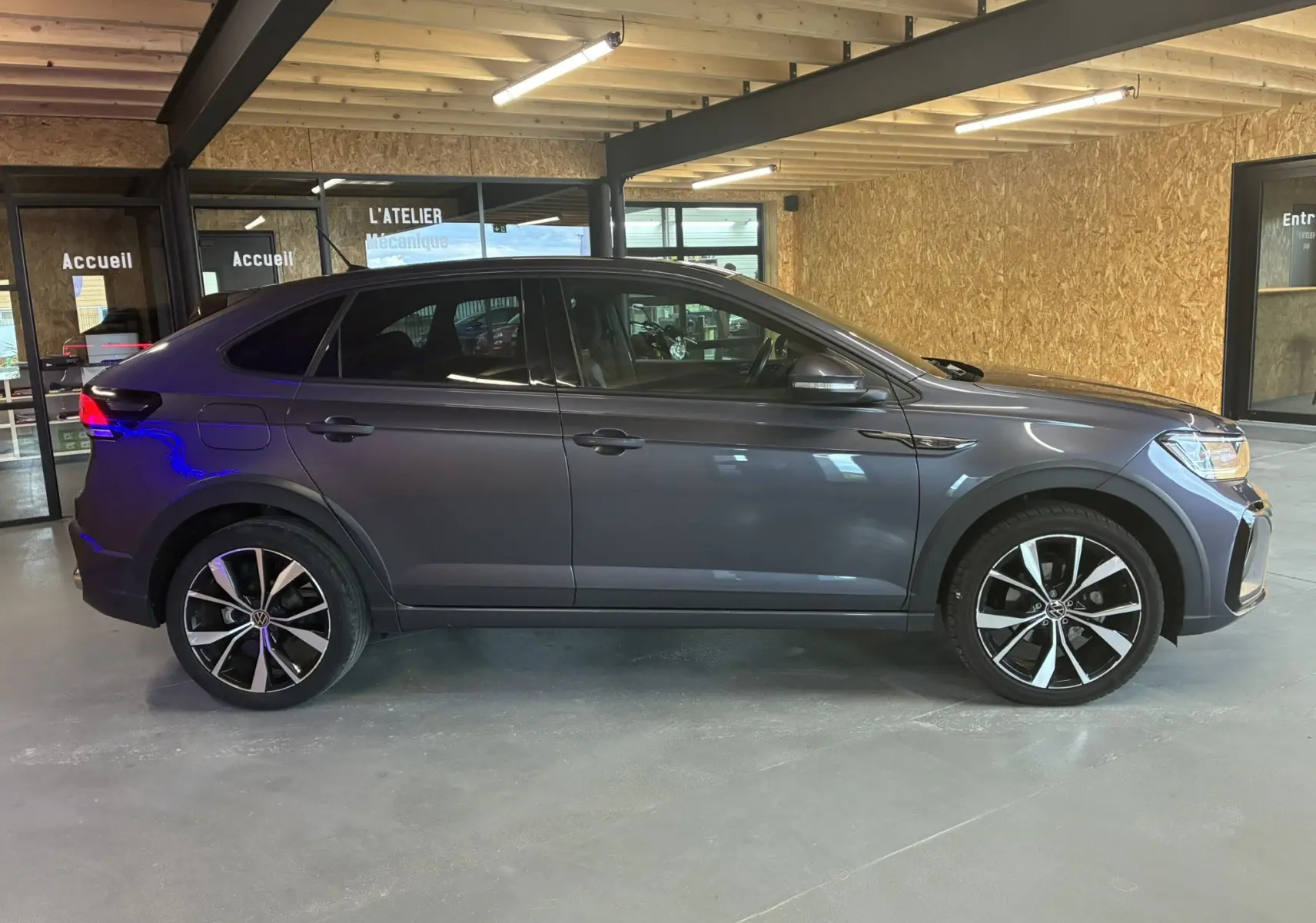Volkswagen Taigo 1.5 TSI 150 R-LINE gris vu de profil côté gauche, avec jantes alliage noires et détails sportifs.