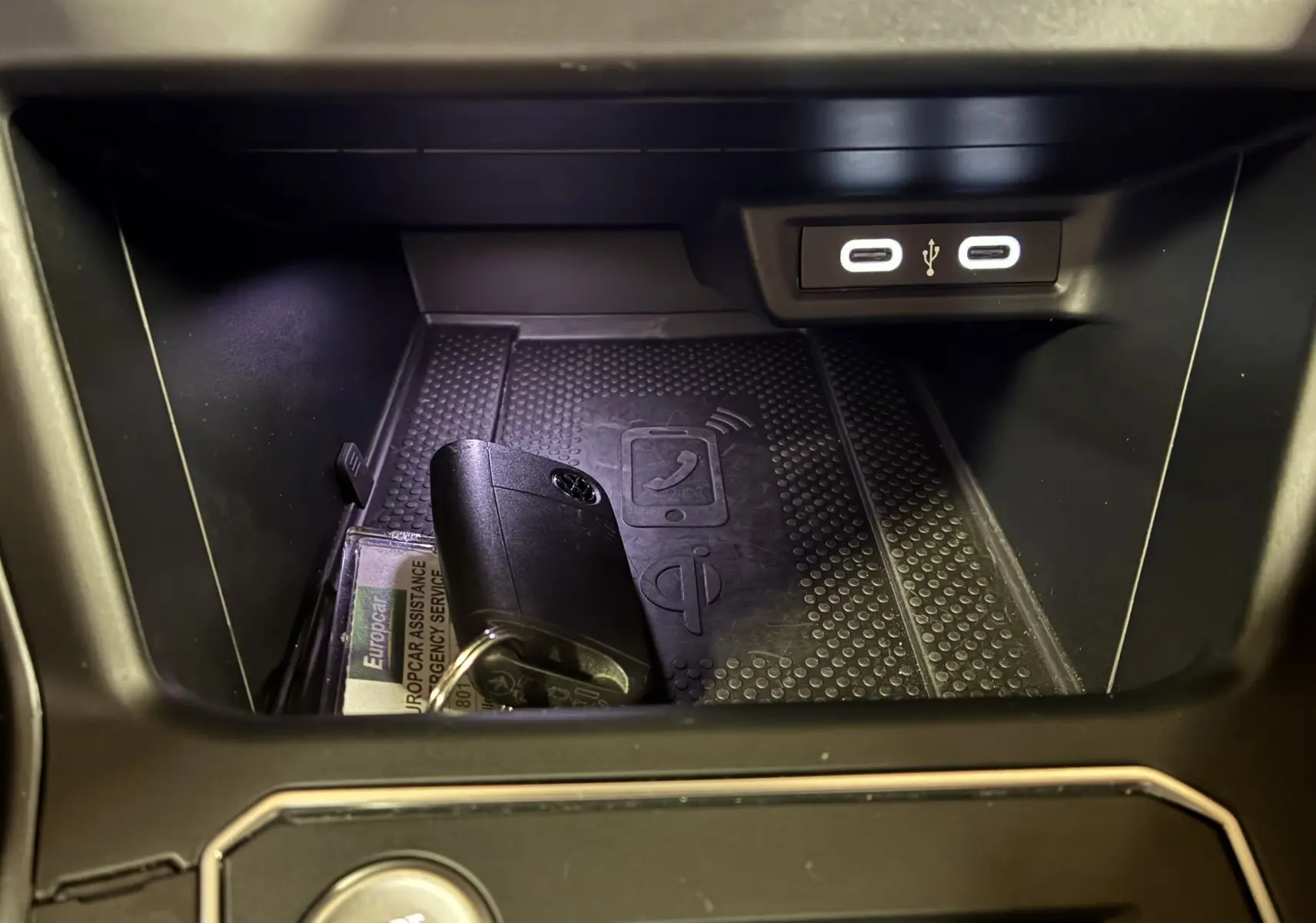 Gros plan sur la console centrale du Volkswagen Taigo gris, montrant un espace de rangement avec clé et ports USB éclairés.