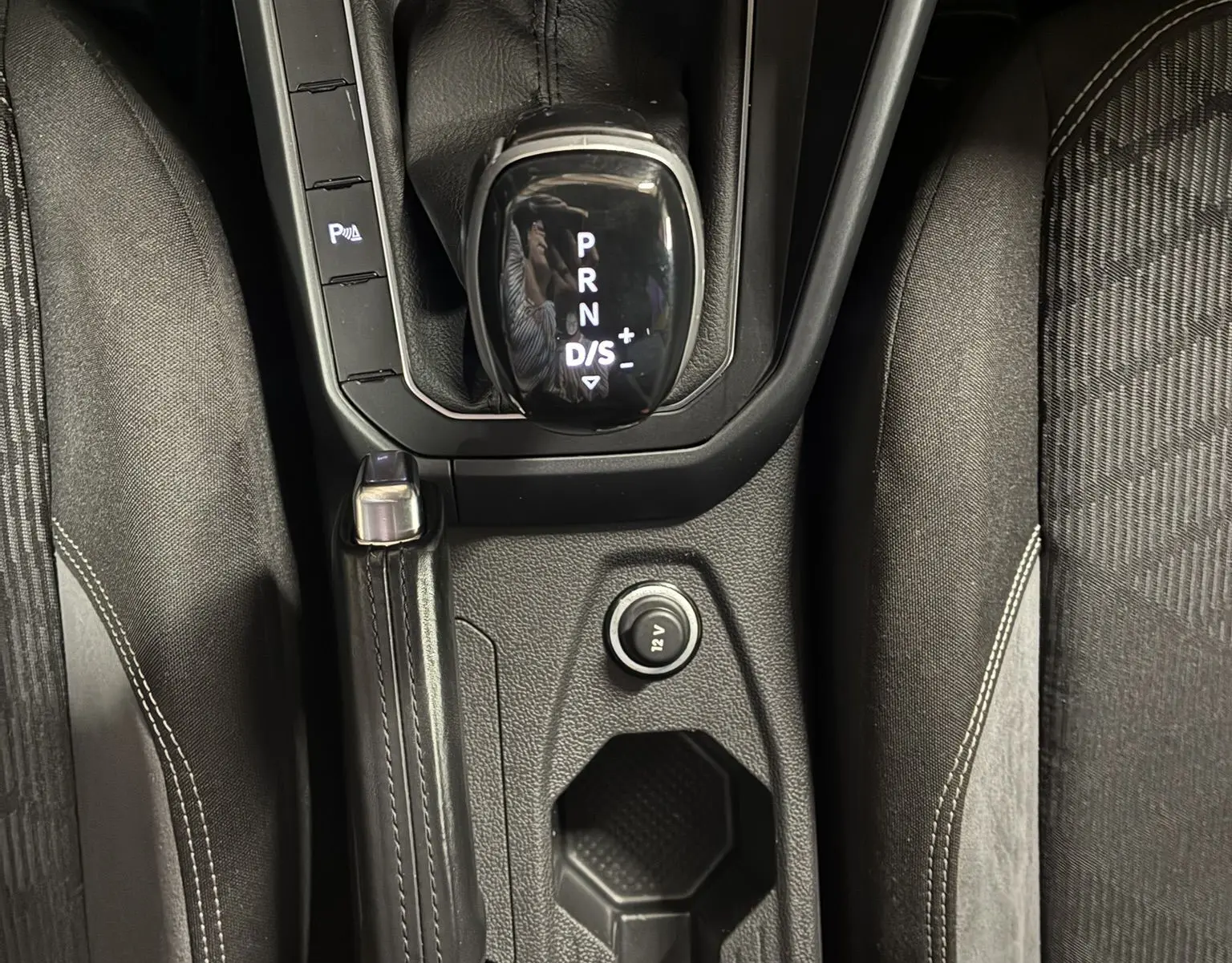 Vue plongeante sur la console centrale grise du Volkswagen Taigo 2023, montrant levier de vitesses automatique et frein à main.