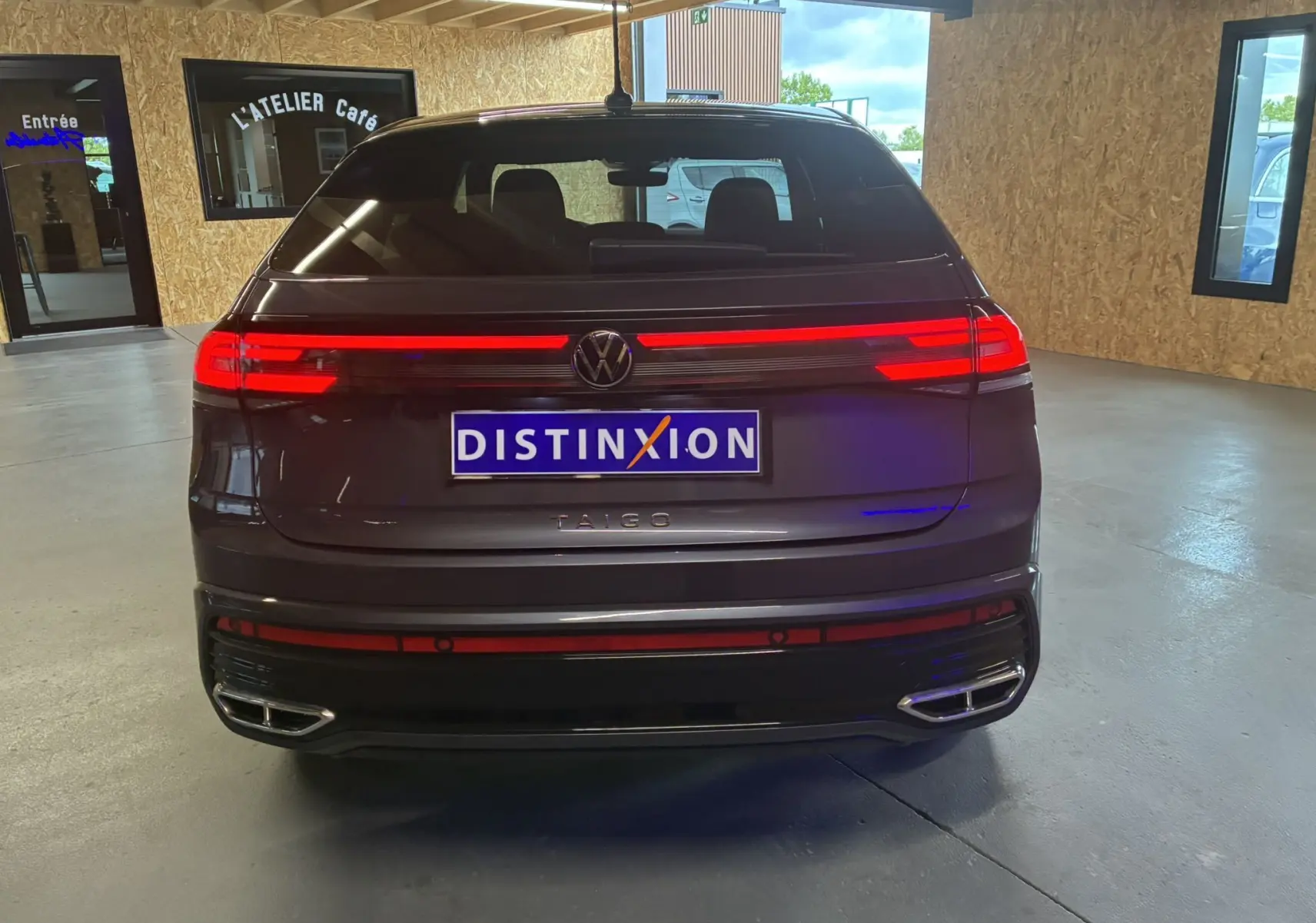 Vue arrière d'un Volkswagen Taigo gris 2023 avec feux LED allumés et double sortie d'échappement chromée.