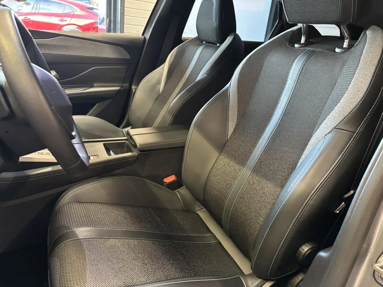 Vue intérieure rapprochée des sièges avant en sellerie tri matières noire avec surpiqûres bleues du Peugeot 308 SW gris clair.