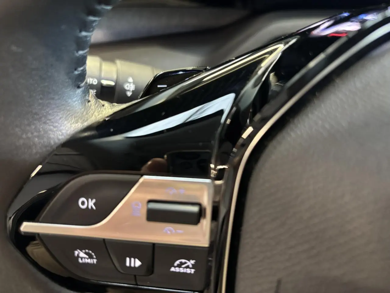 Gros plan sur les commandes au volant noir brillant de la Peugeot 308 SW 2024, avec boutons multifonctions éclairés.