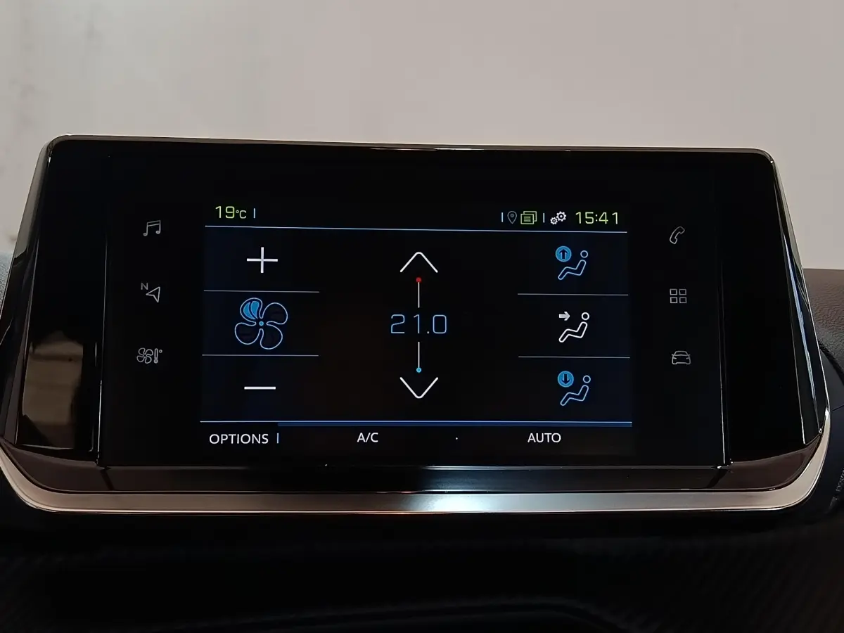 Écran tactile central noir affichant la climatisation à 21°C dans une Peugeot 208 électrique blanche.