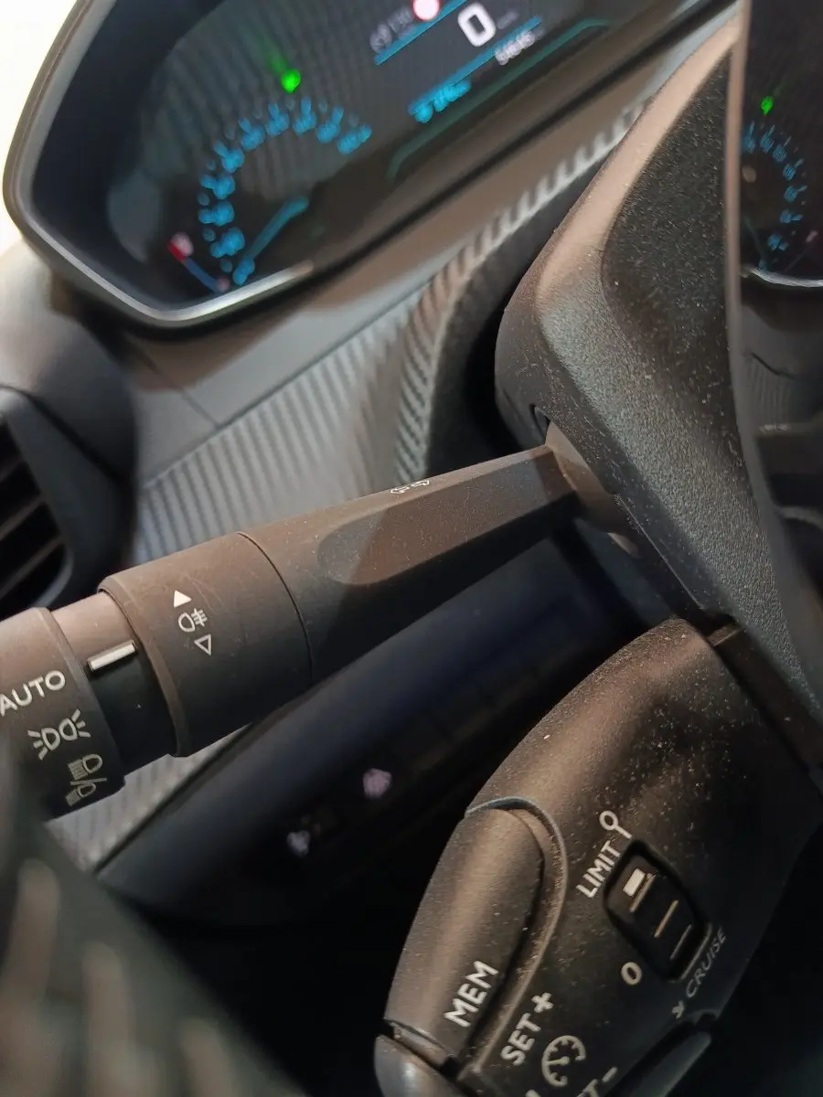 Détail intérieur du volant Peugeot 208 électrique blanc 2020, avec commandes de régulateur et affichage numérique.