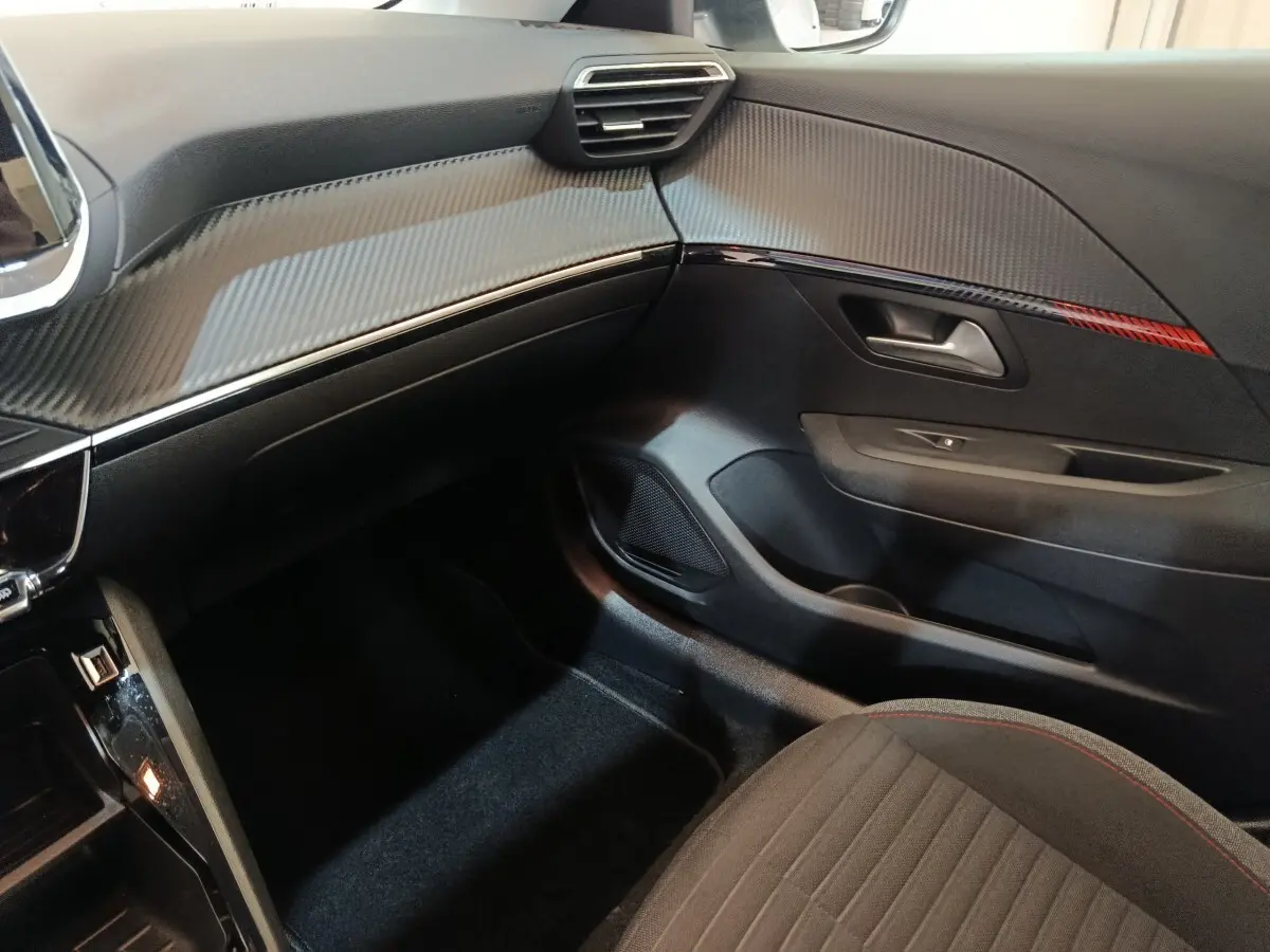 Vue intérieure côté passager de la Peugeot 208 Electrique Active Business 2020 avec tableau de bord noir et détails rouges.