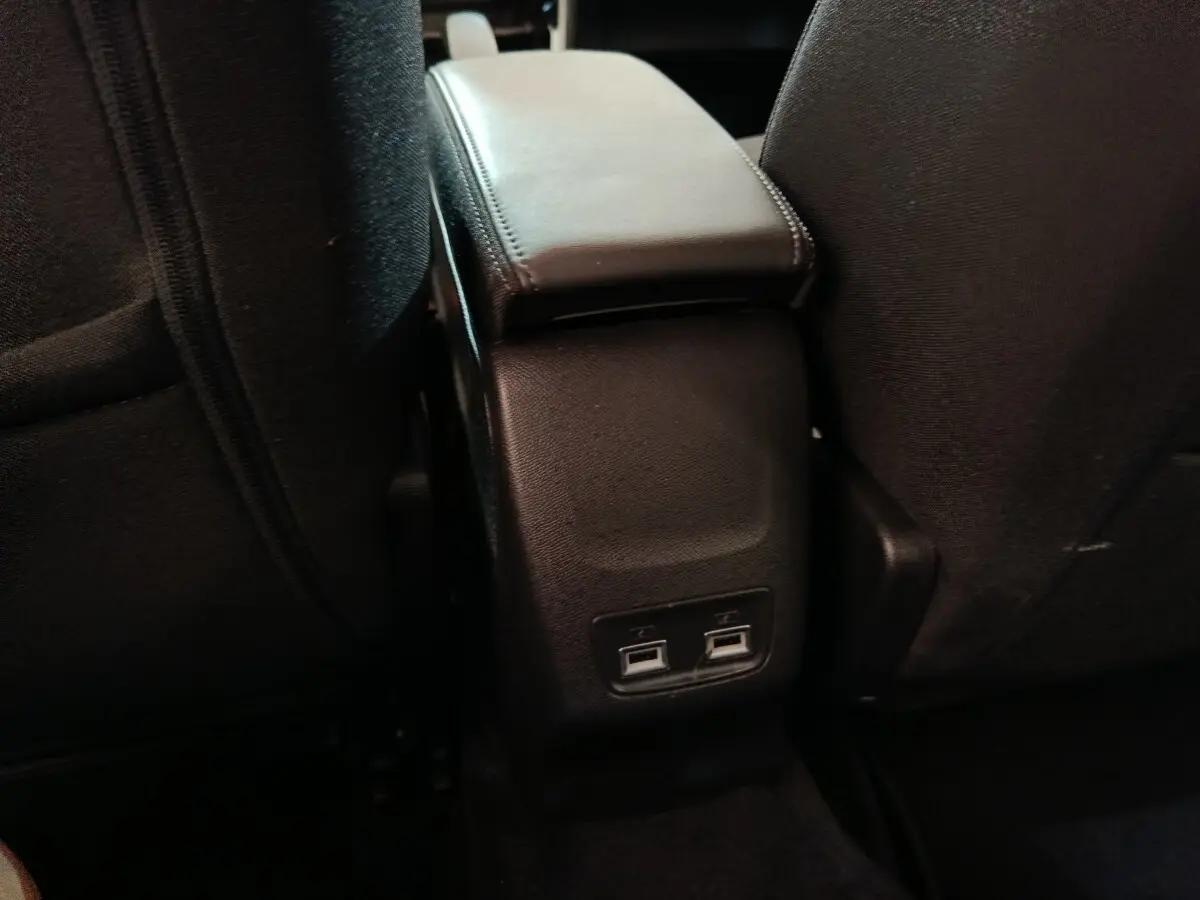 Vue rapprochée de la console centrale arrière avec accoudoir noir et deux ports USB dans une Peugeot 208 blanche électrique.