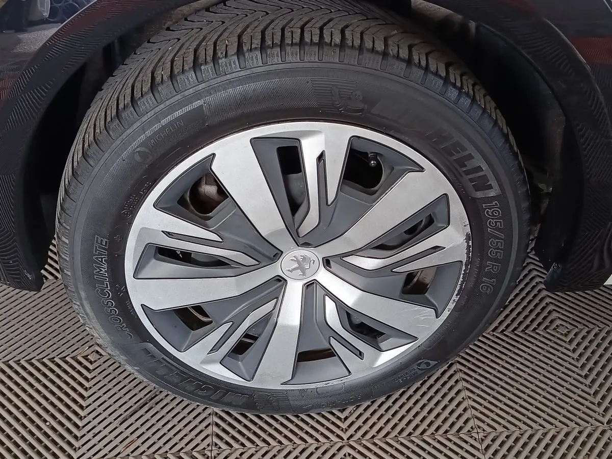 Gros plan sur la roue avant droite de la Peugeot 208 électrique blanche, avec jante en alliage au design moderne.