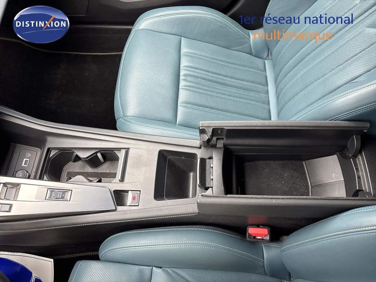 Vue plongeante sur l'intérieur de la Peugeot 308 SW hybride, montrant les sièges en cuir bleu et la console centrale ouverte.