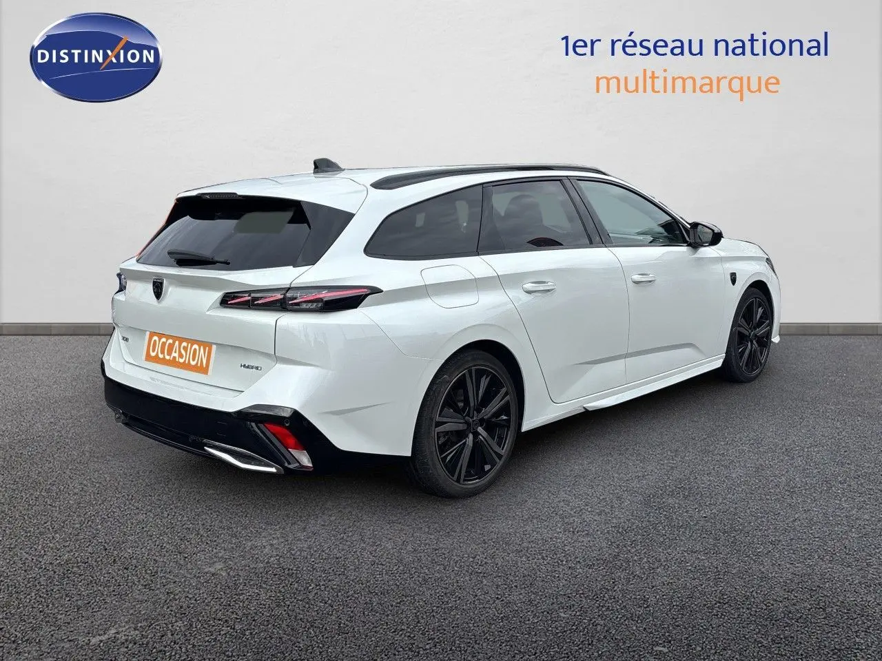 Peugeot 308 SW hybride blanc nacré, vue 3/4 arrière droit, jantes noires et feux arrière LED distinctifs.