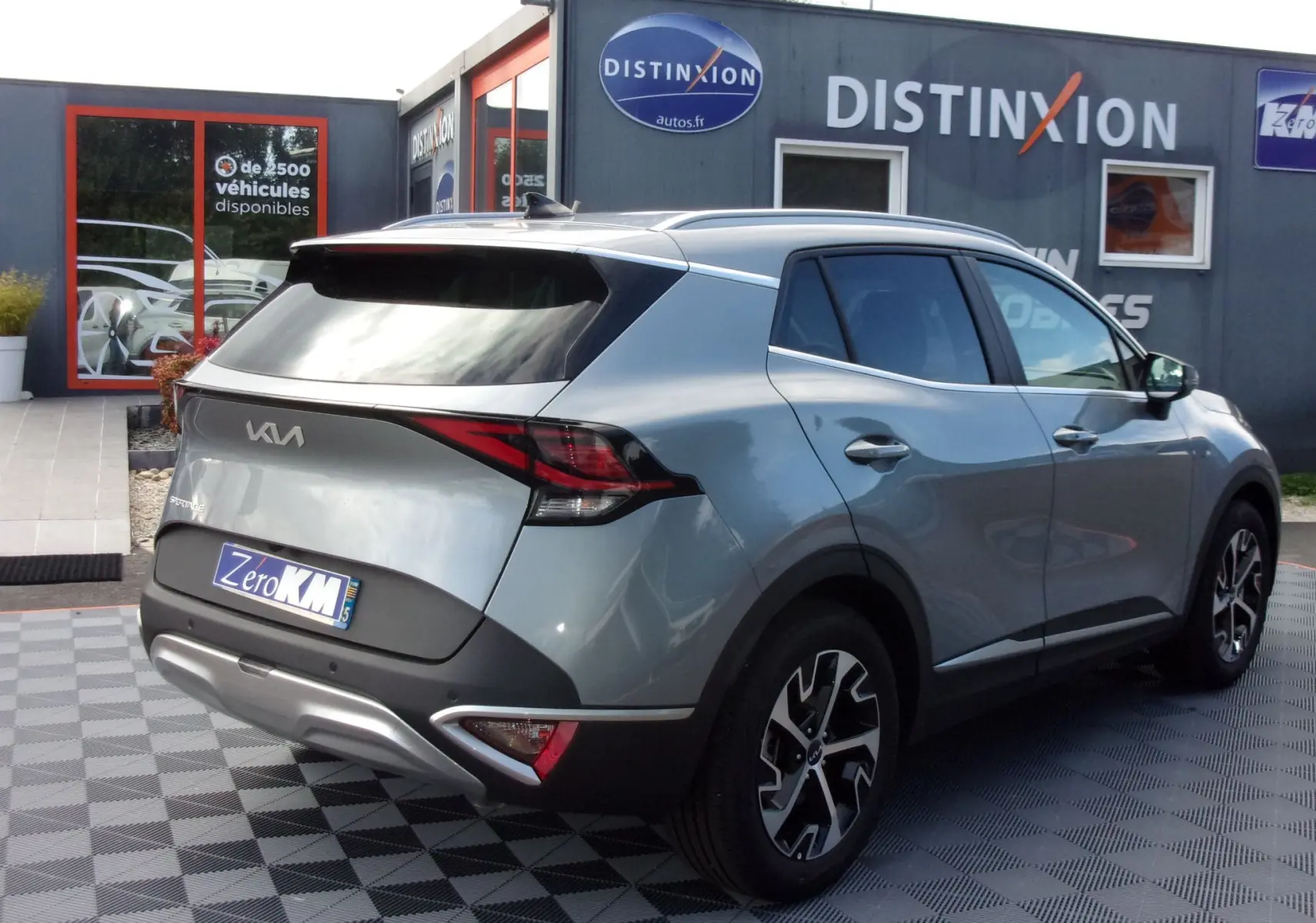 Vue 3/4 arrière droite d'un KIA SPORTAGE gris perle 2025 avec jantes alliage et feux arrière LED distinctifs.