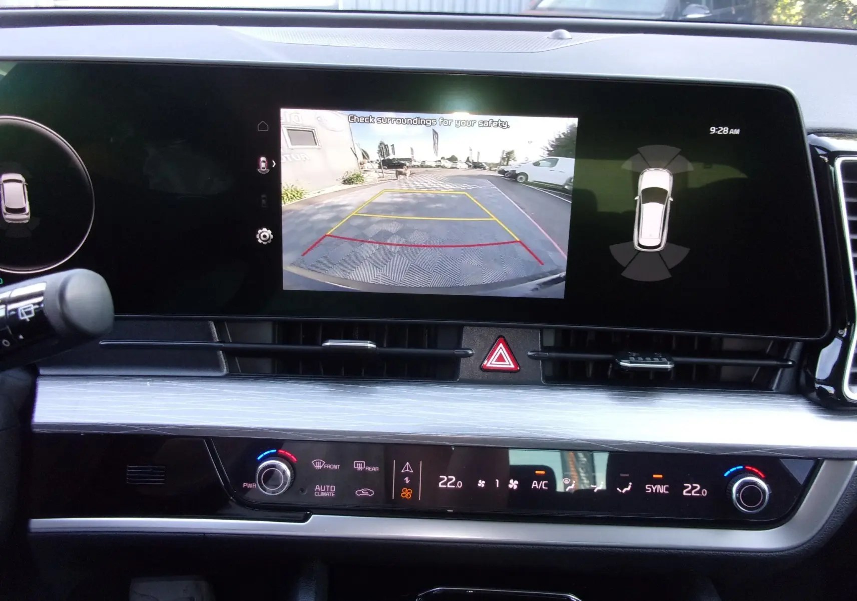 Vue intérieure du tableau de bord du KIA Sportage 2025, écran tactile affichant la caméra de recul et commandes climatisation.